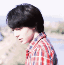 a young man in a plaid shirt looks down at something