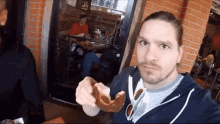 a man is eating a pretzel in front of a brick wall