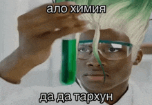 a man with glasses and green hair holds a test tube with a green liquid in it