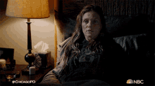 a woman is laying in bed with a lamp and a box of tissues and the hashtag #chicagopd