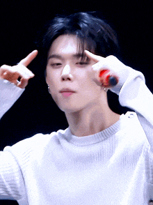 a man in a white sweater is making a peace sign with his fingers