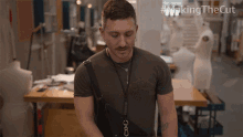 a man with a lanyard around his neck is standing in a room with the words making the cut on the bottom right
