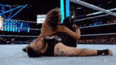 two men are wrestling in a wrestling ring and one of them has a tattoo on his back
