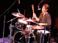 a man is playing drums in front of a microphone in a dark room