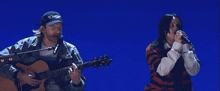 a man playing a guitar next to a woman singing
