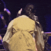a woman in a yellow vest is standing on a stage .