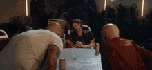 a group of men are sitting around a table with cans of soda