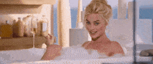 a woman is taking a bath in a bathtub while holding a glass of wine .