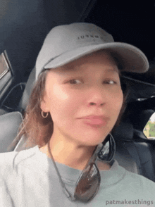 a woman wearing a hat and sunglasses is sitting in a car