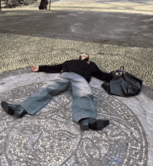 a person is laying on the ground with a black bag