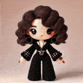 a crocheted doll is wearing a black outfit and earrings