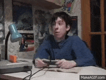 a man is sitting at a desk playing a video game on a console .