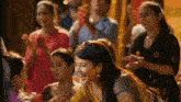 a woman is dancing in front of a crowd of people at a festival .