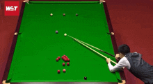 a man is playing snooker on a pool table with a wst logo in the corner
