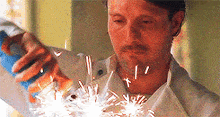 a man in a white shirt is holding a can of soda and sparklers .