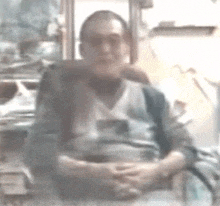 a man is sitting in a chair with his hands folded in front of him .