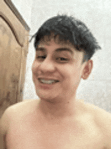 a shirtless young man is smiling in front of a mirror .