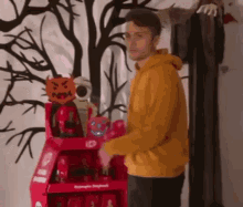 a man in a yellow hoodie is standing in front of a red display case .