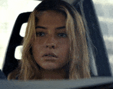 a close up of a woman 's face in a car looking out the window
