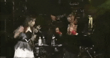 a woman in a gothic dress is standing next to a man in a skeleton costume on stage .