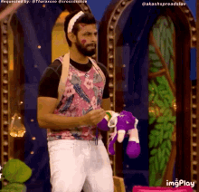 a man in a floral shirt is holding a stuffed animal in his hand ..