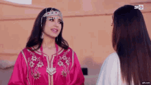 a woman in a pink dress is talking to another woman in a white dress ..