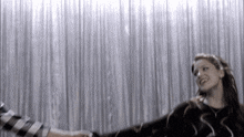 a woman stands in front of a silver curtain