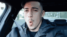 a young man is sitting in the back seat of a car with his mouth open