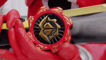 a person in a red glove is holding a red object with a gold symbol on it
