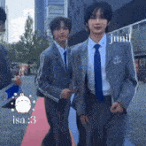 two men in suits and ties are walking on a red carpet
