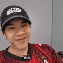 a man wearing a black hat and a red shirt is smiling and says yeah