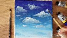 a person is painting a blue sky with white clouds