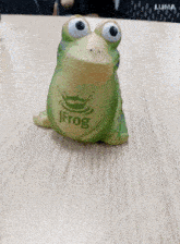 a green frog with the word jfrog on it sits on a wooden table