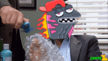 a man in a suit is sitting at a table with a cartoon character on his head