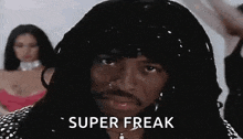 a man with long hair and a beard is wearing a wig and earrings and says `` super freak '' .
