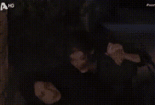 a man in a black shirt is holding a microphone in a dark room .