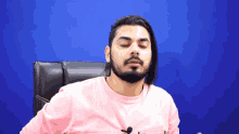 a man with long hair and a beard is wearing a pink shirt with a microphone on it