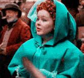 a woman with red hair wearing a green cape and gloves