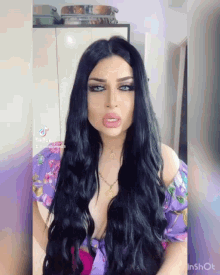a woman with long black hair is wearing a purple top and a gold necklace