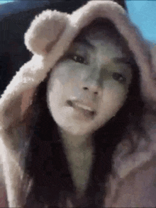 a close up of a woman wearing a teddy bear hood .