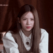 a woman with long hair wearing a white shirt and a brown vest