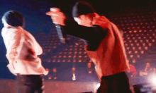 a man is holding a microphone while another man stands in front of him