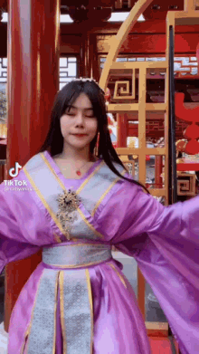 a woman in a purple costume is standing in front of a building .