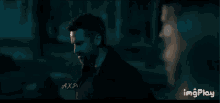 a man with a beard is standing next to a woman in a dark room .