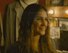 a woman is smiling in front of a mirror with a picture of a man on it