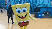 a spongebob mascot stands in front of a rollercoaster