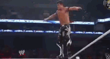 a wrestler is flying through the air during a match in front of a crowd .