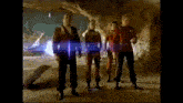 a group of men are standing in a cave with a blue light coming out of it .