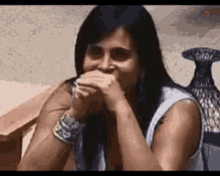 a woman with long dark hair is covering her mouth with her hands .