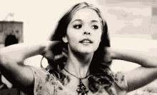 a black and white photo of a woman holding her hair .